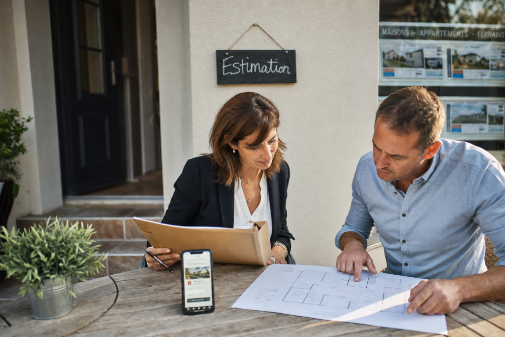 Conseiller immobilier indépendant avec dossier d’estimation devant une maison